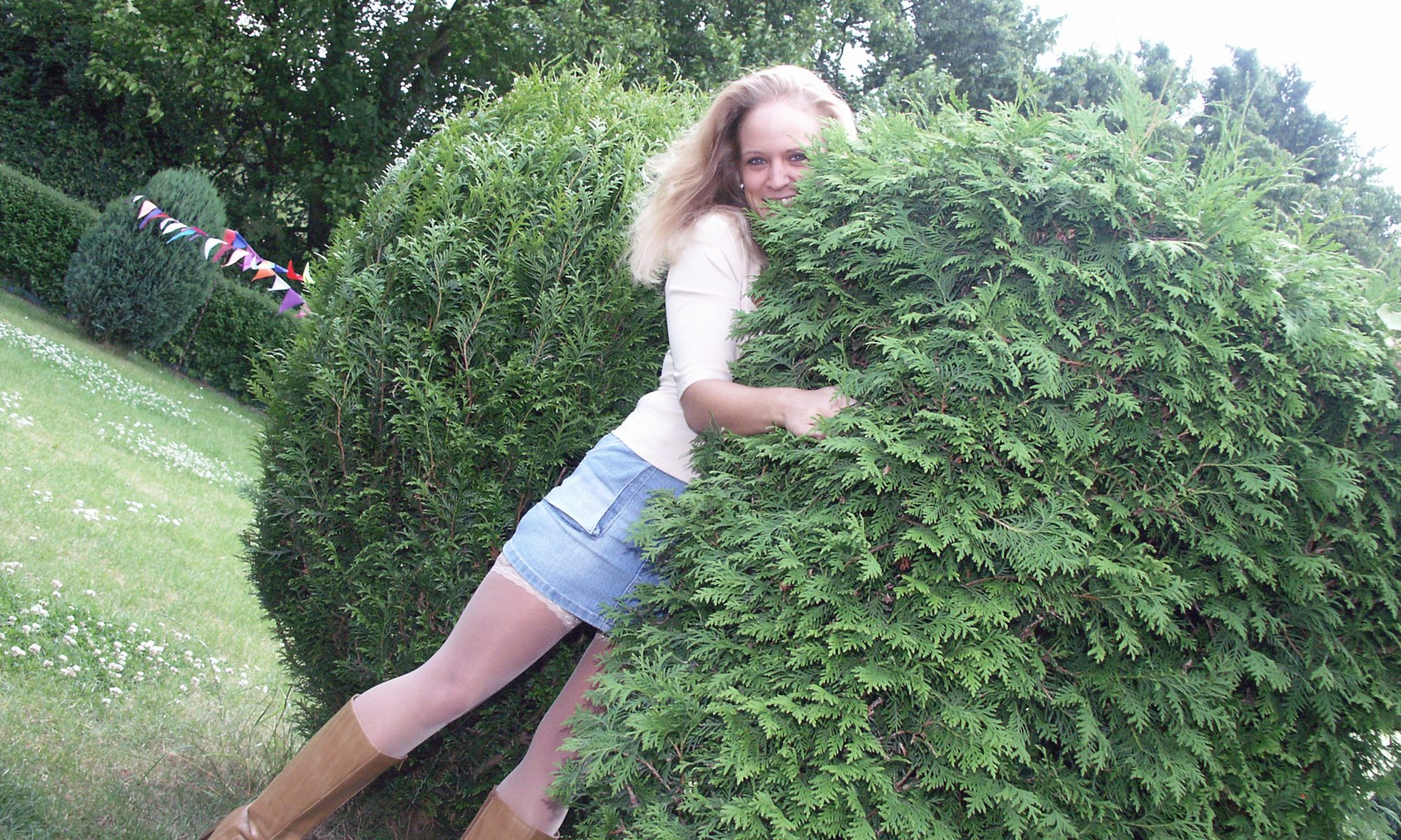 Blondine umarmt die Hecke